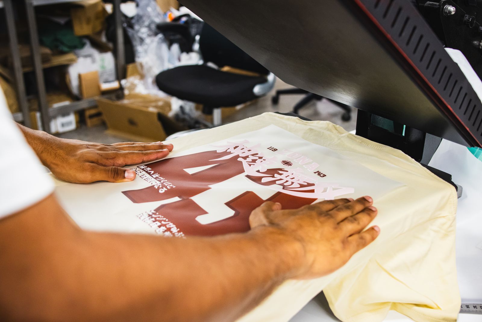 Film DTF posé sur un t-shirt crème, sous la presse à chaud de l'atelier