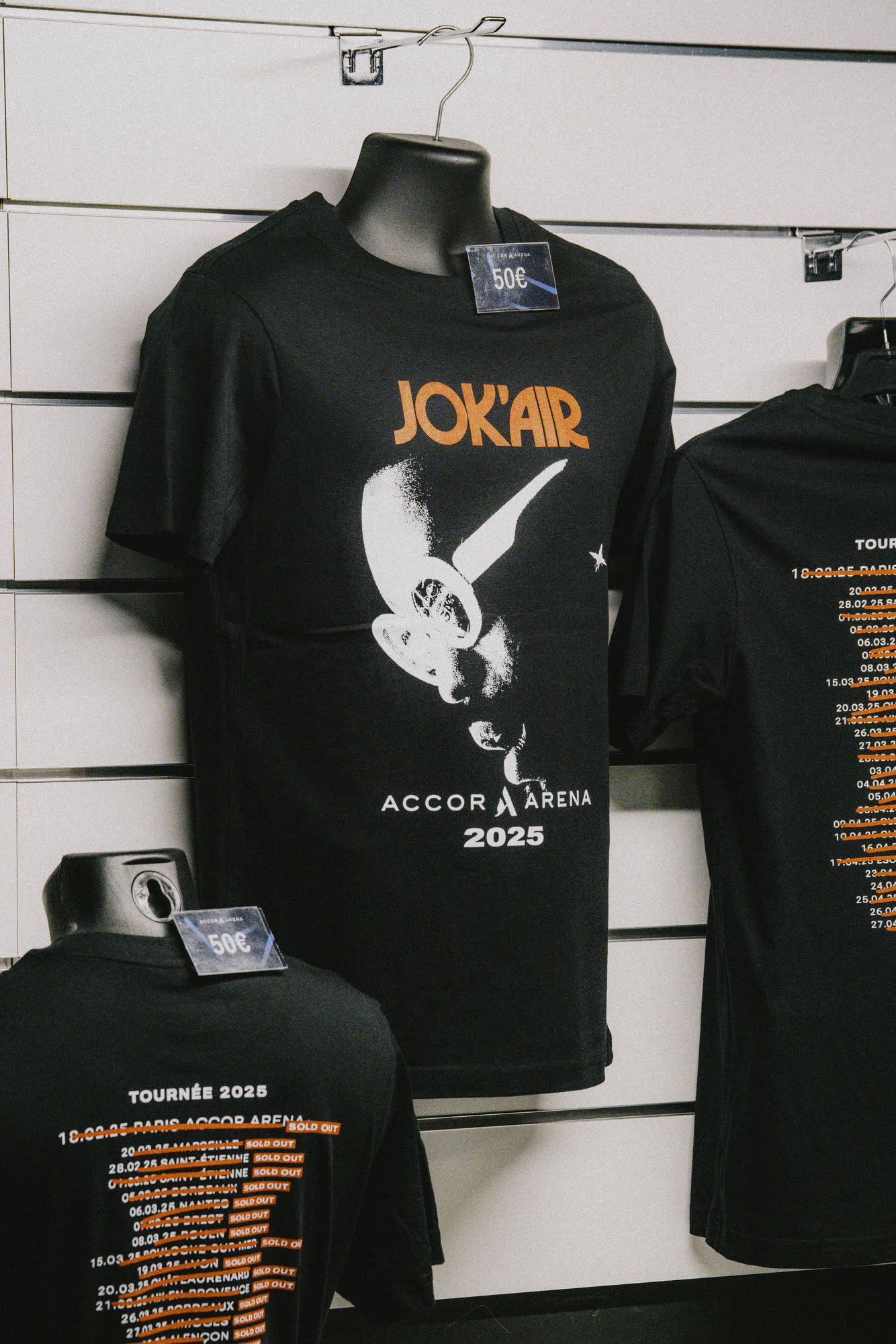 T-shirt noir de la tournée Jok'Air, visuel orange et mention Accor Arena 2025