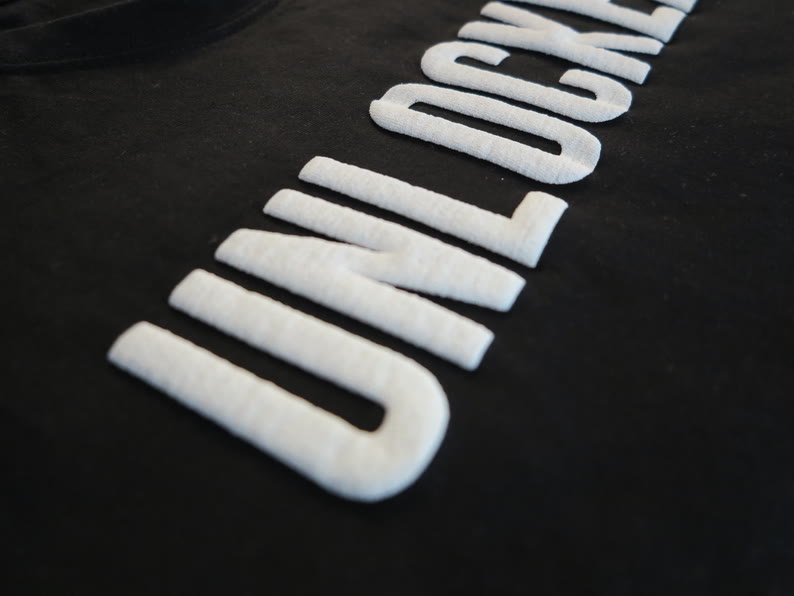 Marquage sérigraphié blanc en relief sur coton noir, vu de très près